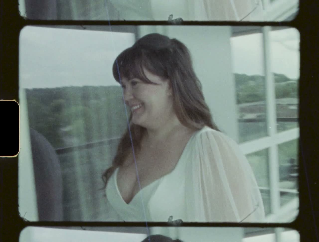 Bride smiling by a window before the ceremony