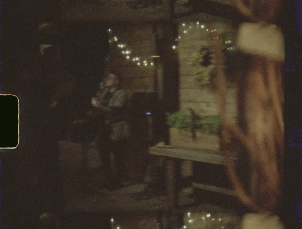 A musician playing under string lights