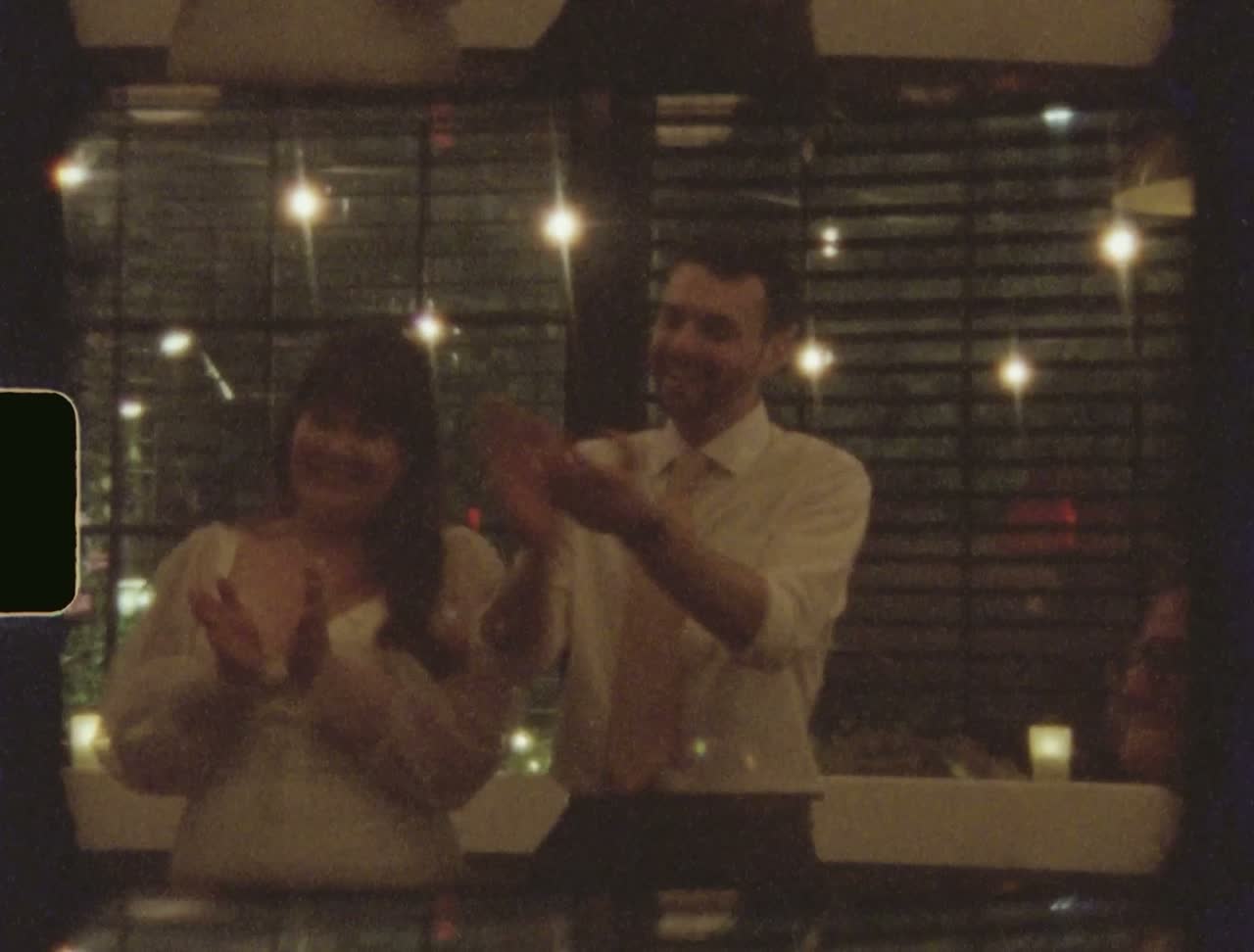 Couple clapping along at the reception under string lights