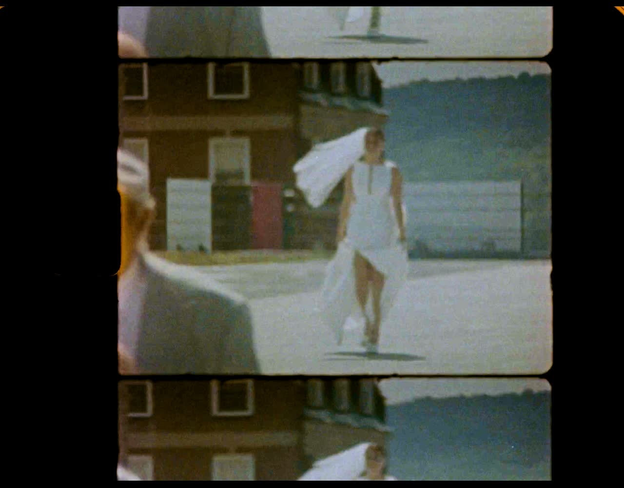 Bride walking across a rooftop in the sun, dress trailing